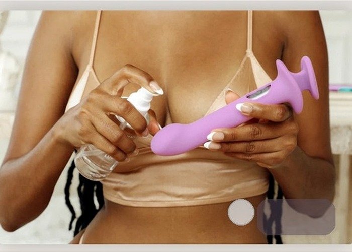 A person cleaning a curved vibrator beside a spray bottle to compare how targeted motion styles fit into real care routines.