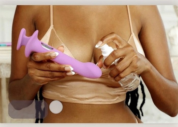 A small vibrator and lubricant bottle arranged on a bedside table for pressure and comfort planning after a piercing heals.