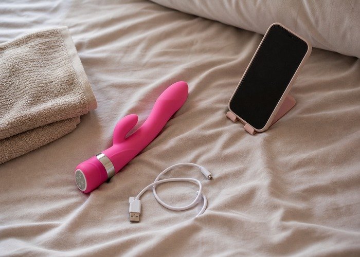 A realistic compact adult toy and pouch in a private bedroom setting for an adults-only aftercare guide.