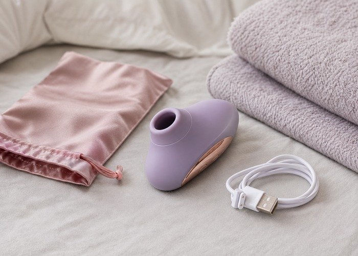 A close bedside setup with three vibrator styles, lubricant, and a towel arranged to compare sensation pattern and contact style.