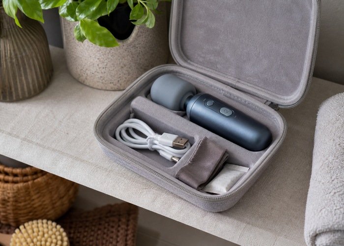 A rechargeable personal wellness device stored in an open fabric case with a dry cloth.
