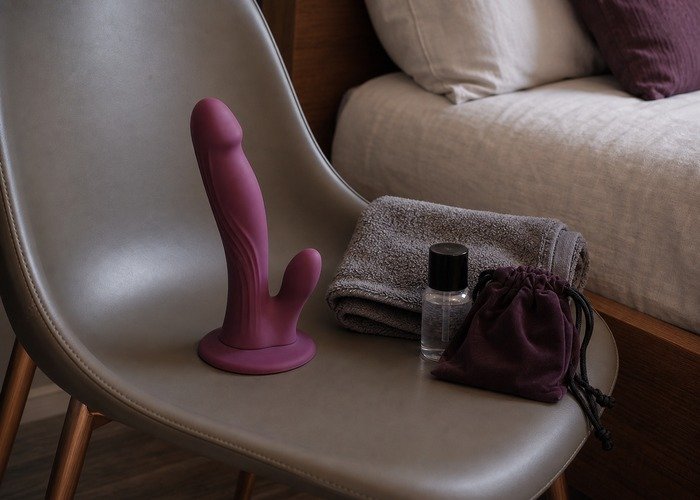 A cleaned suction-cup dildo, towel, pouch, and lubricant arranged to connect surface choice with easy cleanup and storage.