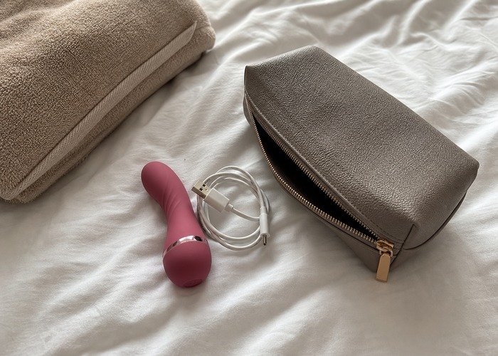 A tidy carry pouch, compact toy, charging cable, and folded towel arranged to show an easy hotel-room reset after travel.